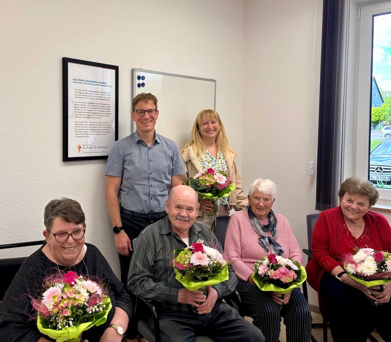 Mitglieder des neuen Heimbeirats und weitere Personen mit Blumensträußen